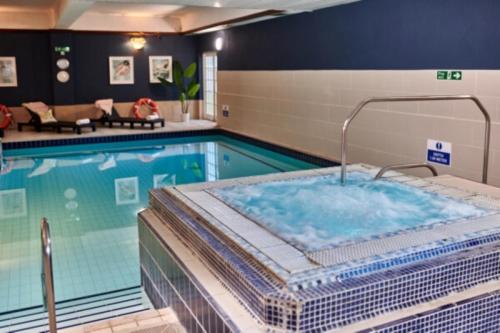 uma piscina com banheira de hidromassagem num quarto de hotel em Burnham Beeches Hotel em Slough