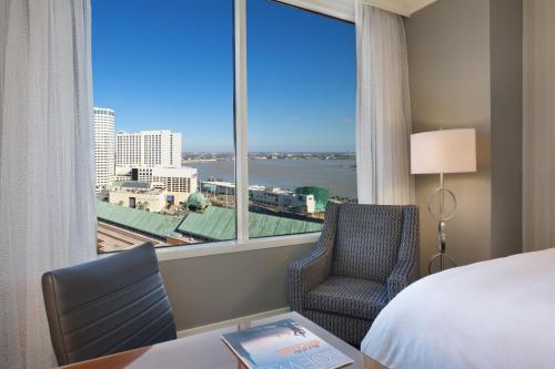 ニューオーリンズにあるロウズ ニューオーリンズ ホテルのベッド、デスク、窓が備わるホテルルームです。