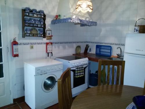 a kitchen with a washing machine and a refrigerator at Casa da Beija - House Azores in Furnas