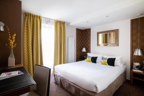 una camera d'albergo con un grande letto e una scrivania di Hôtel Le Colisée a Parigi