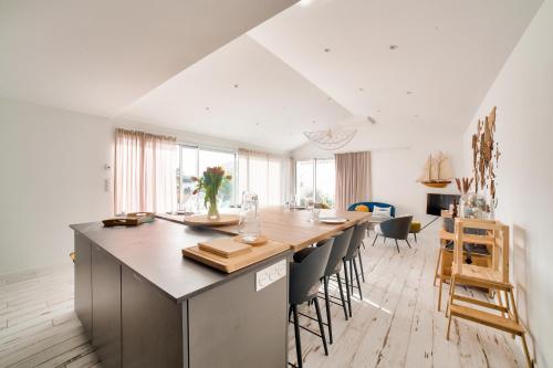 une cuisine avec une longue île dotée d'une table et de chaises dans l'établissement Maison pour 9 - Jacuzzi - 300m de la plage, à Noirmoutier-en-l'lle