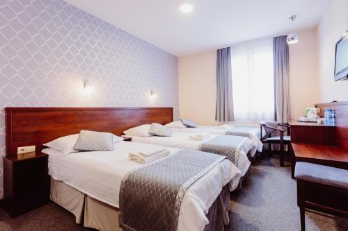 a hotel room with three beds and a desk at Hotel Fero Express POKOJE KLIMATYZOWANE AC in Kraków