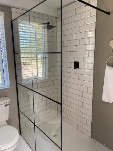 a glass shower door in a bathroom with a toilet at The Stables on Drew Avenue in Howick