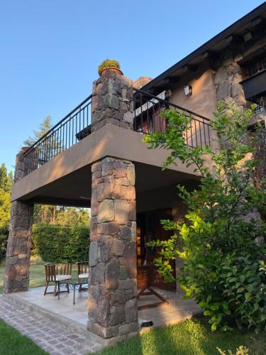 a stone house with a balcony and a patio at Alto Chacras Cottage in Chacras de Coria