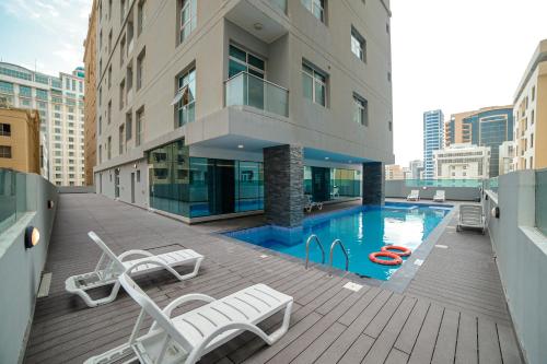 einen Balkon mit Stühlen und einen Pool auf einem Gebäude in der Unterkunft JC SUITES in Manama