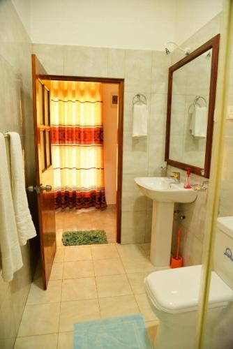 a bathroom with a sink and a toilet and a mirror at Neel's Guest House in Kosgoda