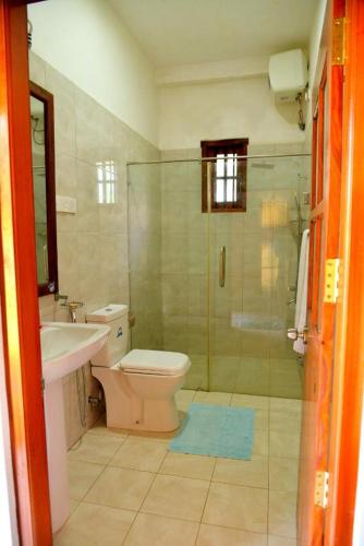 y baño con ducha, aseo y lavamanos. en Neel's Guest House, en Kosgoda