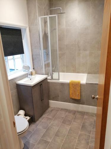 een badkamer met een bad, een toilet en een wastafel bij Halt Cottage in Bridgnorth