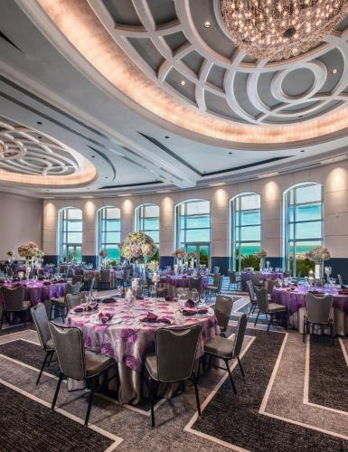 a ballroom with purple tables and chairs and a chandelier at Loews Miami Beach Hotel in Miami Beach