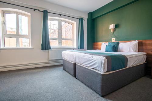 a bedroom with a large bed with green walls and windows at Castlefield Hotel in Manchester