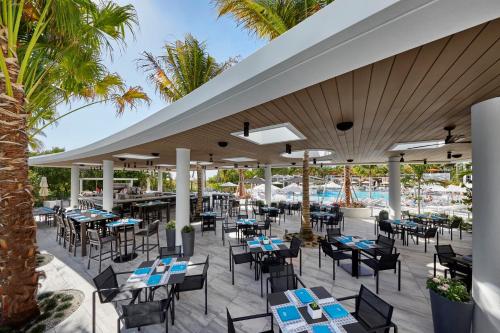 an outdoor restaurant with tables and chairs and palm trees at Loews Miami Beach Hotel in Miami Beach