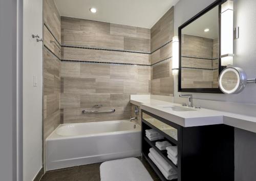 a bathroom with a tub and a sink and a mirror at Loews Miami Beach Hotel in Miami Beach