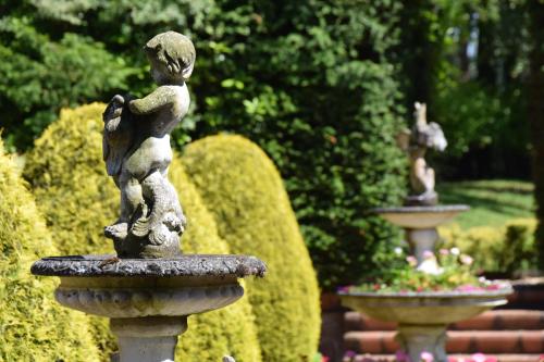 a statue of a child in a fountain in a garden at Nunsmere Hall Hotel in Oakmere
