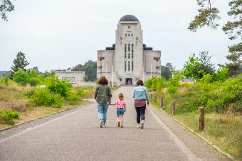 two women and a little girl walking down a road at Comfort Rooms by EuroParcs de Zanding in Otterlo