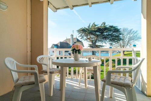 d'une table et de chaises blanches sur un balcon avec vue sur l'océan. dans l'établissement Côté Ouest - Appt avec piscine partagée, à Bénodet
