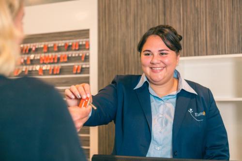 a woman in a suit and tie holding a orange lighter at Comfort Rooms by EuroParcs de Zanding in Otterlo