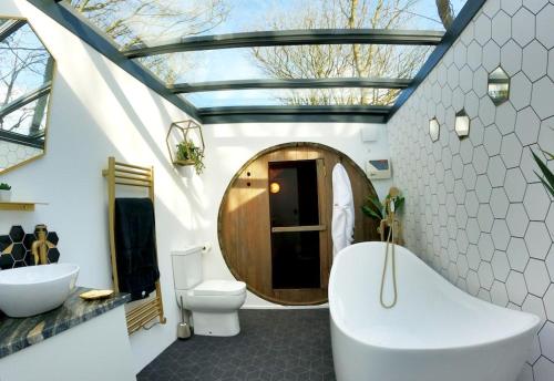 a bathroom with a tub and a toilet and a sink at Romance - Stargazing - Hot tub & sauna! in Camborne
