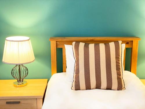 a bed with a pillow and a lamp on a night stand at Catcune Superior Suite in Gorebridge