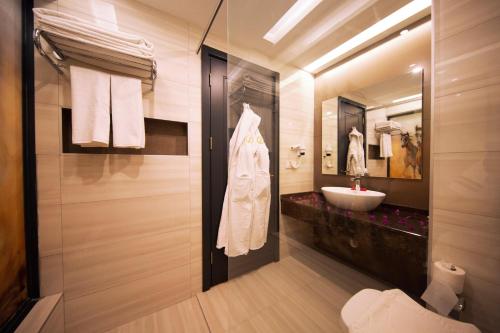 a bathroom with a sink and a white robe at Sey Beach Hotel & Spa in Alanya