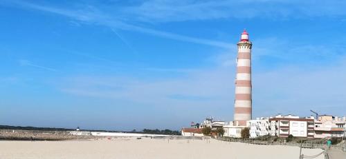 a lighthouse on the beach next to a building at Manny's place - by the sea in Gafanha da Nazaré