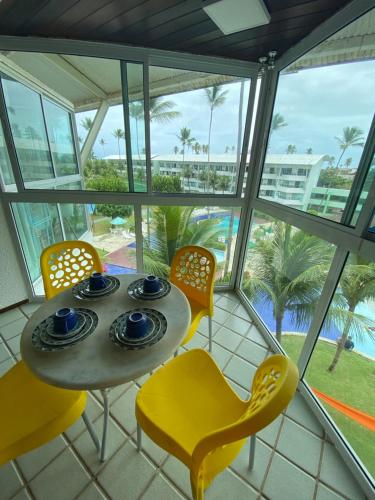 a table and chairs in a room with a view of the ocean at Ancorar Flat - dois quartos in Porto De Galinhas