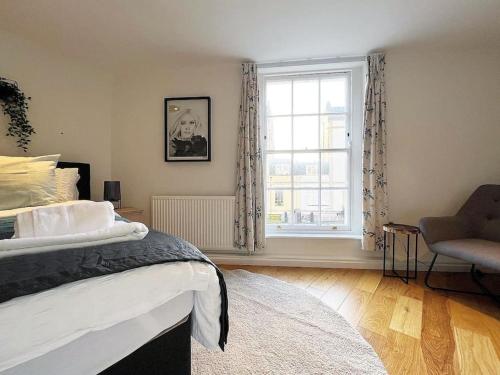 ein Schlafzimmer mit einem Bett, einem Fenster und einem Stuhl in der Unterkunft Quirky 3 Bedroom Town House in Clifton, Bristol in Bristol