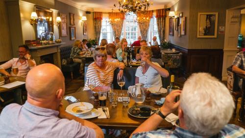 eine Gruppe von Menschen, die an einem Tisch in einem Restaurant sitzen in der Unterkunft The Swan at Tarporley in Tarporley