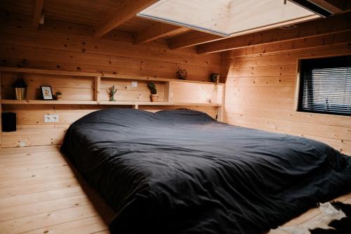 een slaapkamer met een zwart bed in een houten kamer bij Tiny house op de Veluwe in Beekbergen