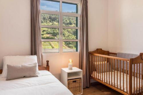 um quarto para bebés com um berço e uma janela em Casa da Olides - T3 em Santana