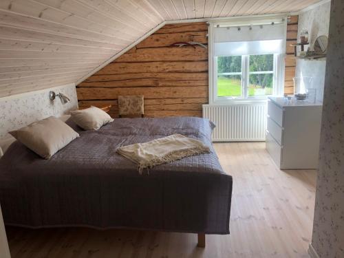 um quarto com uma cama e uma parede de madeira em Mysig lantlig stuga, Nycklarör em Korsberga