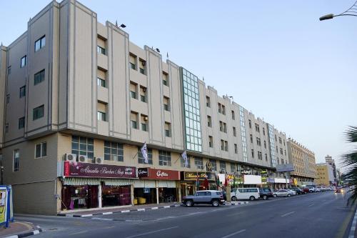 un gran edificio en una calle de la ciudad con coches aparcados delante en شقق منصور بلازا للشقق المخدومة, en Dammam