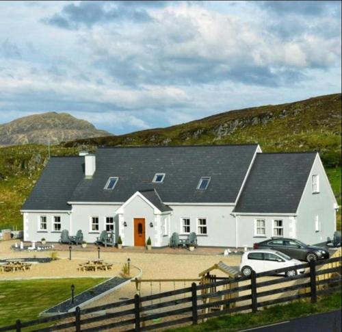 una casa bianca con macchine parcheggiate di fronte di Slieve League House B&B a Teelin