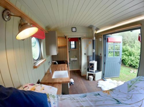 a tiny house with a kitchen and a living room at Romantic Retreat - Luxury Shepherds Hut + Hot Tub! in Camborne