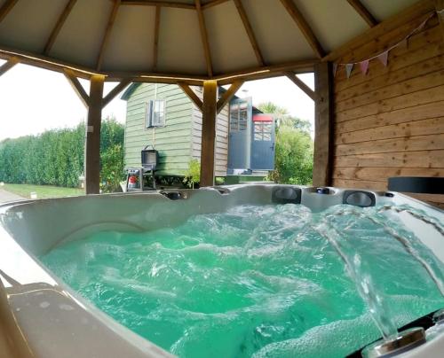 a hot tub in a gazebo with green water at Romantic Retreat - Luxury Shepherds Hut + Hot Tub! in Camborne