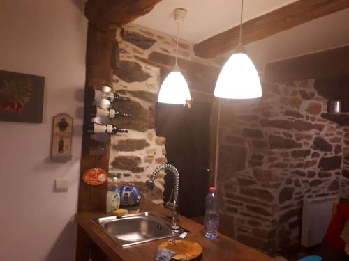 a kitchen with a sink and a stone wall at Petite bergerie en pierres tout confort in Salles-Curan