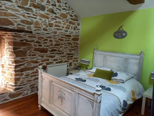 a bedroom with a bed with a stone wall at Petite bergerie en pierres tout confort in Salles-Curan
