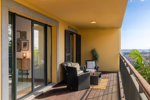 a balcony with two chairs and a television on it at Comboio I by An Island Apart in Funchal