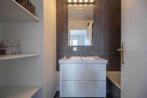 une salle de bain avec un lavabo blanc et un miroir dans l'établissement Appartement Emplacement Idéal de Disney à Paris, à Serris