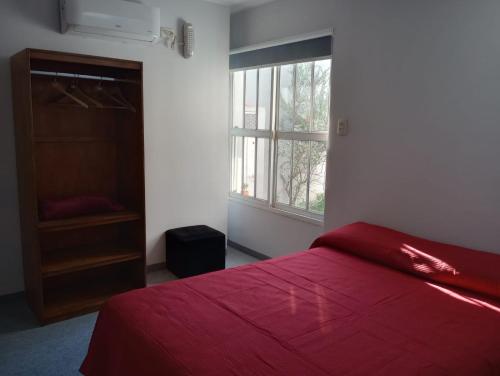 1 dormitorio con cama roja y ventana en El Espacio en Junín