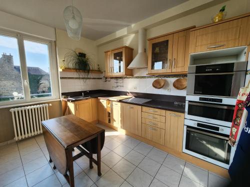 une cuisine avec des armoires en bois et une table à l'intérieur dans l'établissement Mont Naïa, à Pontorson