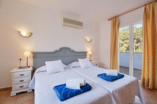 a bedroom with a large white bed with blue towels on it at Monte Violeta in Jávea