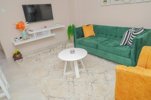 sala de estar con sofá verde y mesa blanca en Lovely 1-bedroom apartment with free parking, en Nairobi