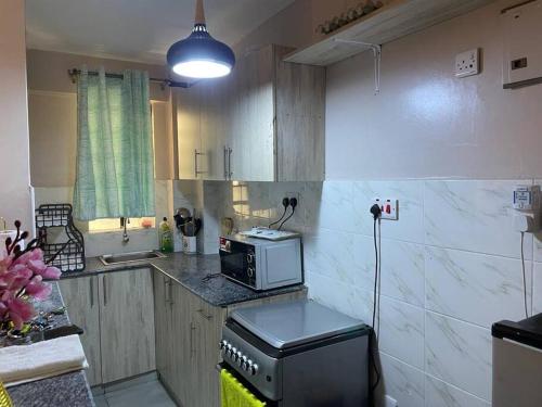 cocina con encimera y microondas en Lovely 1-bedroom apartment with free parking, en Nairobi