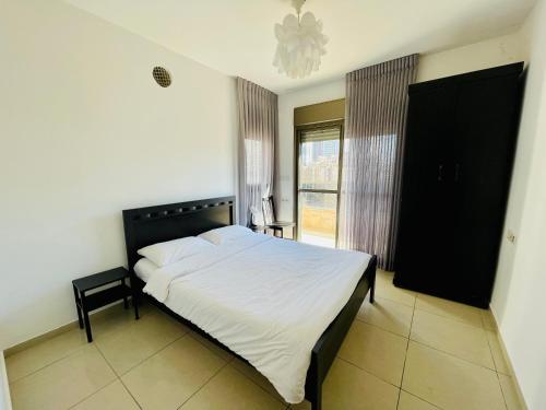 een slaapkamer met een groot bed met een zwart hoofdeinde bij King David Apartment in Netanya