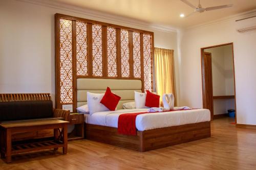 um quarto com uma cama grande e almofadas vermelhas em Thai Beach Resort em Tiruchchendūr