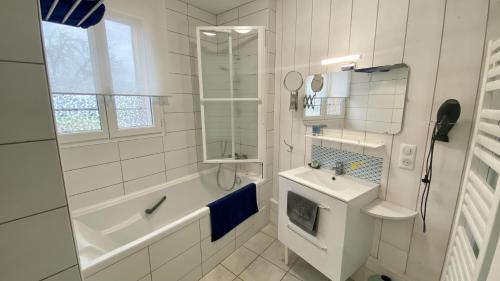 a white bathroom with a tub and a sink at Les Volets Bleus in Saint-Valery-sur-Somme
