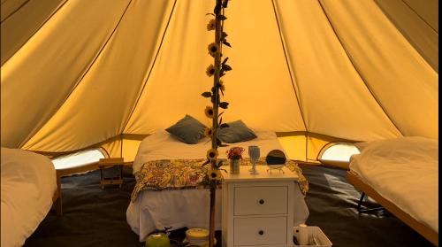 a tent with a bed and a table in it at Strawberry Fields Glamping at Cottrell Family Farm in Wokingham