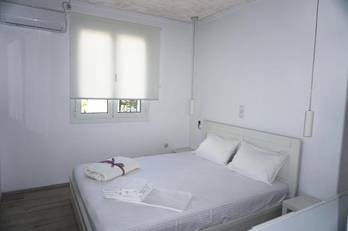 Dormitorio blanco con cama blanca y ventana en Modern Apartment 10mins from the Beach en Kefallonia