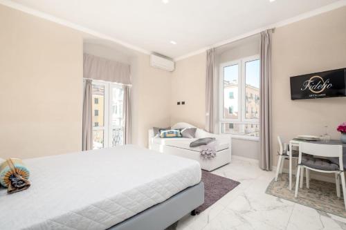 a white bedroom with a bed and a table at Fidelio in La Spezia