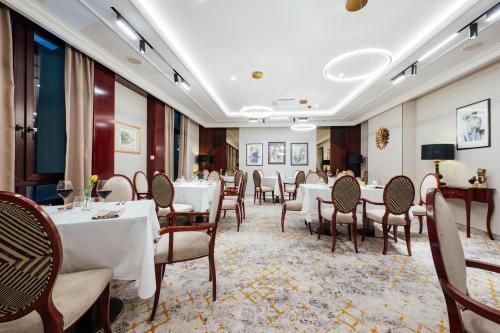 una sala da pranzo con tavoli e sedie bianchi di L`Art Hotel Carei a Carei